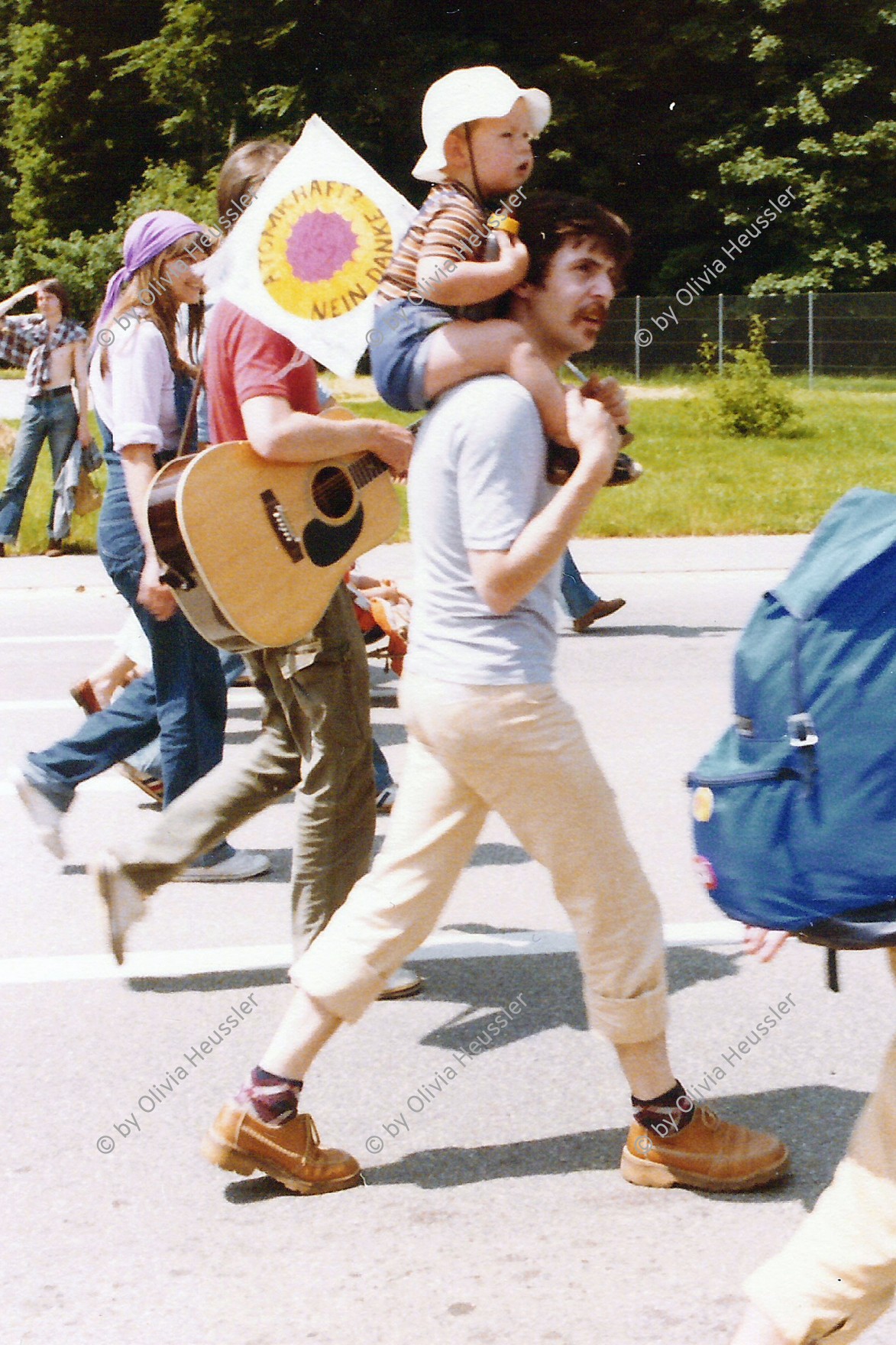 Image of sheet 19790070 photo 3: Pfingstmarsch gegen Atomkraftwerk Gösgen Anti AKW Bewegung 'Stop für AKW Leibstadt' Kanton Aargau 1979 ? Protest Gitarre Rucksack Vater mit Kind auf den Schultern Fahne