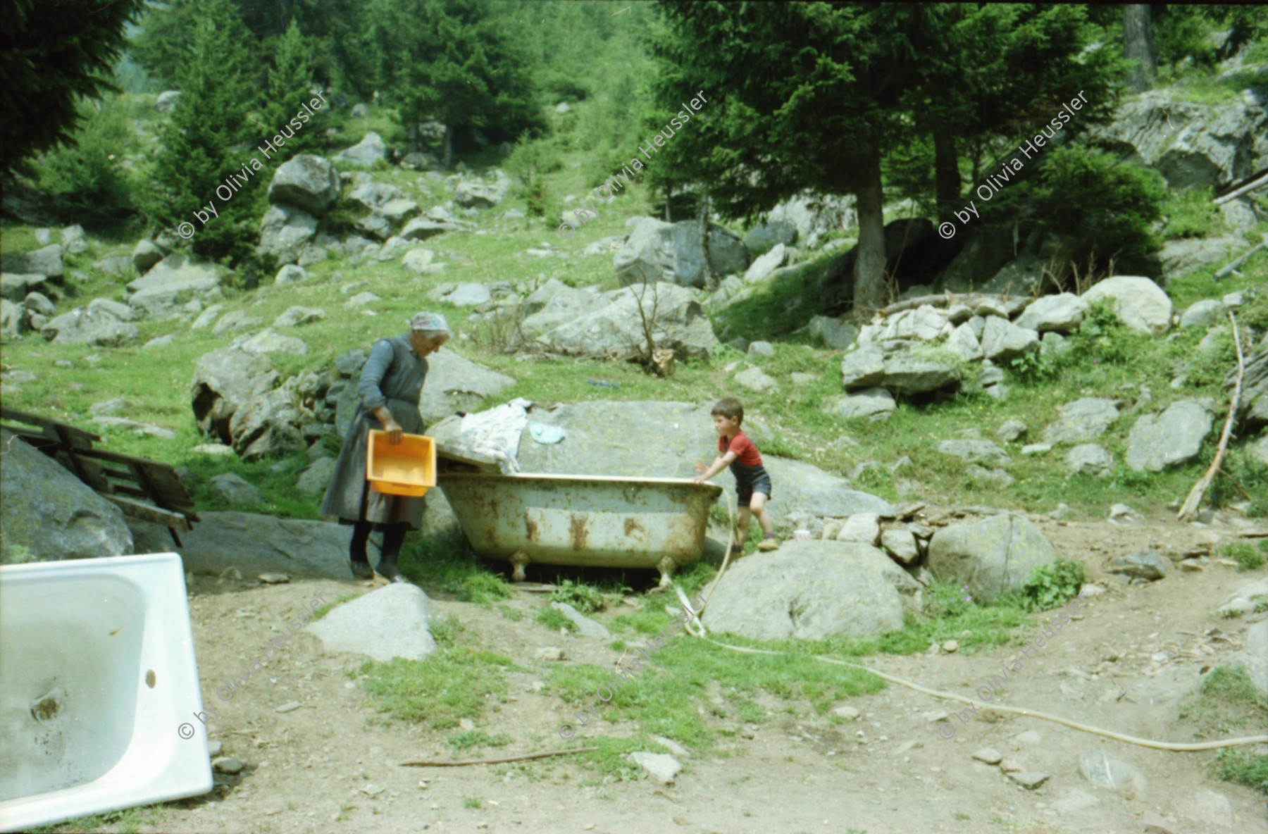 Image of sheet 19800010 photo 11: Frau mit Junge auf der Ziegenalp Badewanne 
Bahnhof Sondrio Italien Mann giesst Topfpflanze