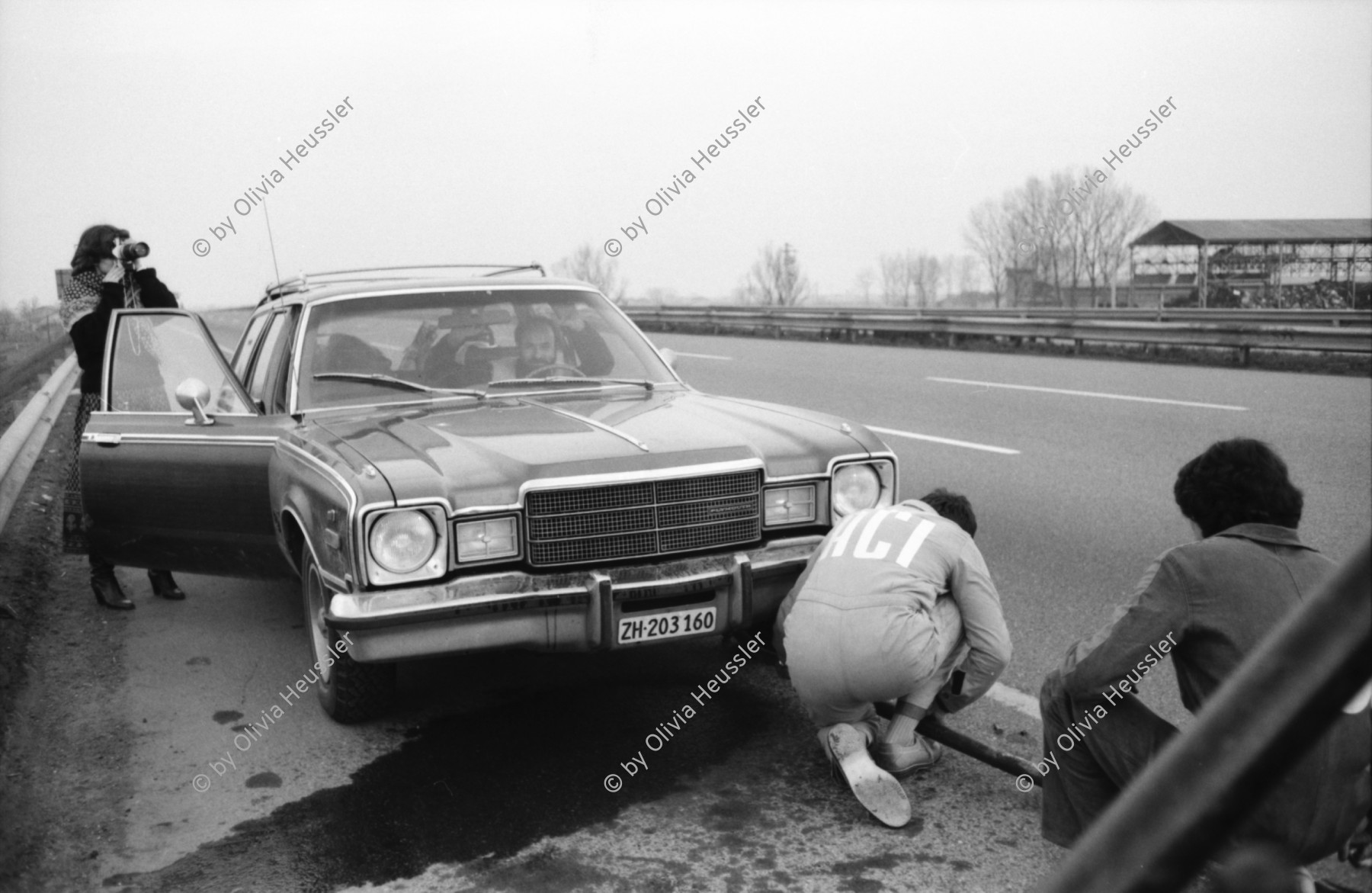 Image of sheet 19800040 photo 26: Frau fotografiert auf Autobahn, während Automechaniker Auto flickt. Italien 1980

8888