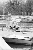 Image of sheet 19800080 photo 3: Demonstration der POCH gegen geplantes Parkhaus unter der Limmat. Mit auf Floss ziehendem Deux Chevaux Döschwo.in der Limmat. 'Parkhäuser vors Volk.' Mein erstes Bild im TA. Bootssteg bei Riviera mit Fraumünster Kirche und Döschwo. 1980 Schweiz Zürich