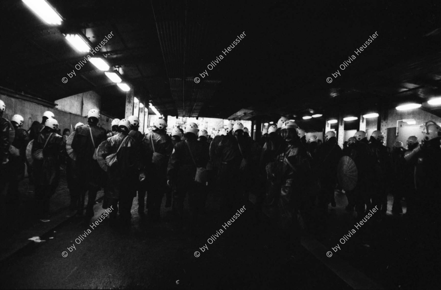 Image of sheet 19800092 photo 30: frtsg. 800091 
Protest in der Unterführung Langstrasse. Sie wird von der Quartiergruppe 'Luft und Lärm' u.a. mit Koni Frei, heutiger Betreiber einiger Gastrobetriebe im Kreis vier 4 besetzt. Tränengas mit Rauchgas Gemisch. Monster brennt. Polizeibeamte, auch Grenadiere genannt mit ihren Schutzschildern in der Unterführung. Videoladen Marcel filmt Nr. 23. Zürich 1980 Laerm Rauch Traenengas