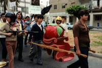 Image of sheet 19800100 photo 31: An der 1. Mai Demonstrations Feier 1980, in Tel Aviv Israel, nehmen 150'000 Menschen teil,  junge Frauen und Männer aus den Kibutz. Sie tragen eine grosse Tomate aus Papier maché mit. Waffe Gewehr
√
A kibbutz (Hebrew: קִבּוּץ / קיבוץ, lit. "gathering, clustering"; plural kibbutzim) is a collective community in Israel that was traditionally based on agriculture. Today, farming has been partly supplanted by other economic branches, including industrial plants and high-tech enterprises.[1] Kibbutzim began as utopian communities, a combination of socialism and Zionism. In recent decades, some kibbutzim have been privatized and changes have been made in the communal lifestyle. A member of a kibbutz is called a kibbutznik (Hebrew: קִבּוּצְנִיק).