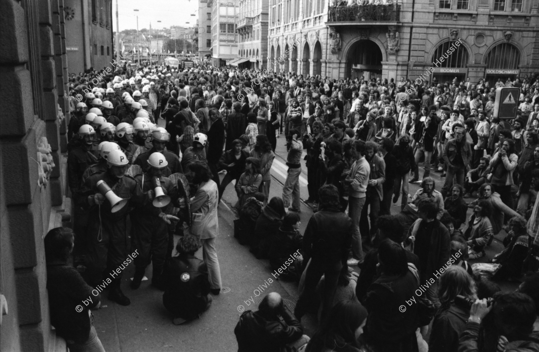 Image of sheet 19800160 photo 28: Demonstrierende versammeln sich vor dem Rathaus: Sie fordern den Gemeinderat zu einer Diskussion auf. Der Gemeinderat verweigert das Gespräch. Die Demonstrierenden harren aus, worauf die Polizei eingreift. 
Zur Forderung eines Autonomen Jugendhauses wird der Platz vor dem Rathaus am Limmatquai besetzt. Sit-In. Polizei Einsatz. Polizeihelme von oben herab. 

Jugendbewegung Bewegig AJZ Zürcher Jugendunruhen Demonstrationen
Zürich Youth movement 1980