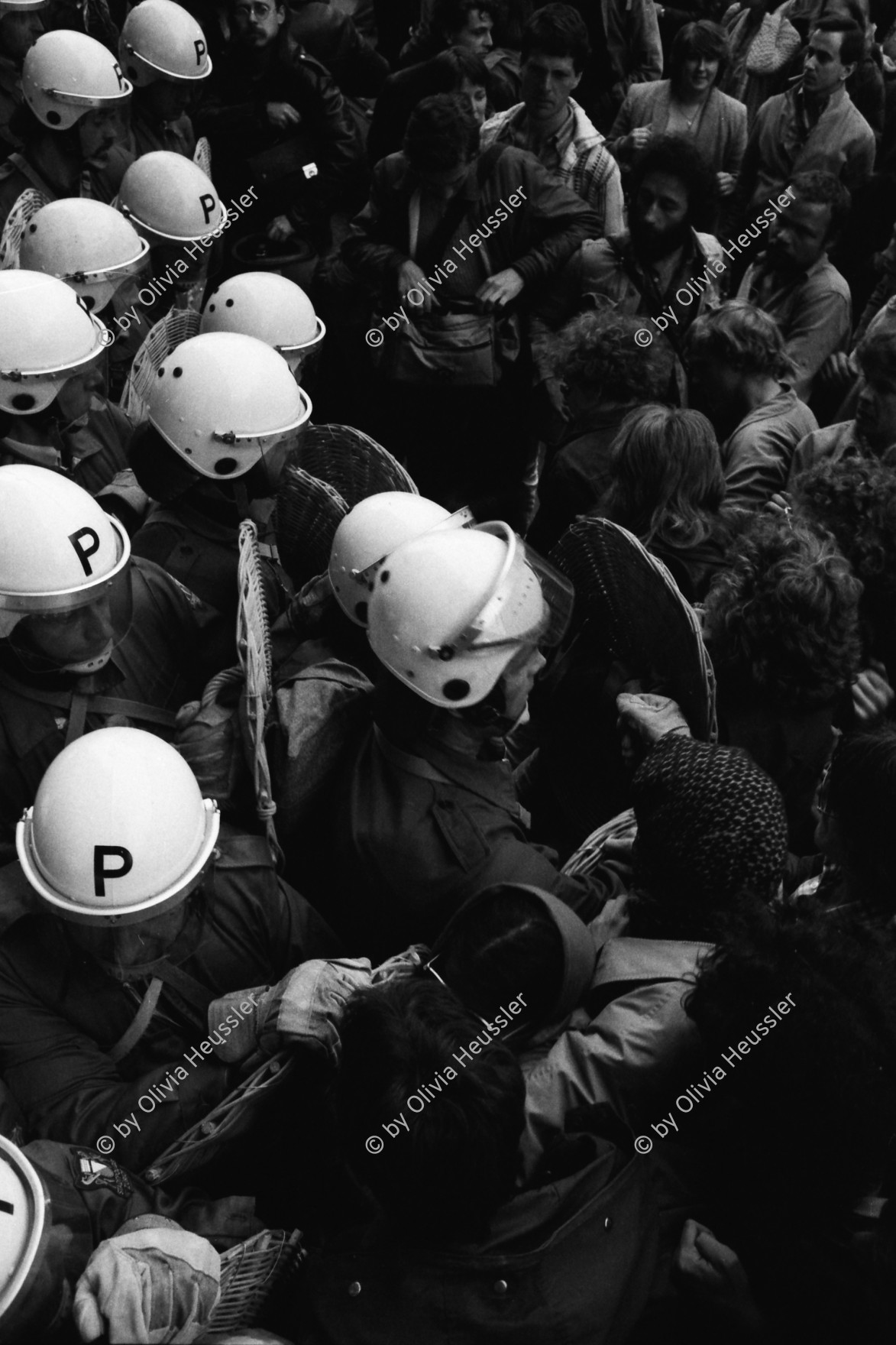 Image of sheet 19800160 photo 36: Demonstrierende versammeln sich vor dem Rathaus: Sie fordern den Gemeinderat zu einer Diskussion auf. Der Gemeinderat verweigert das Gespräch. Die Demonstrierenden harren aus, worauf die Polizei eingreift. 
Zur Forderung eines Autonomen Jugendhauses wird der Platz vor dem Rathaus am Limmatquai besetzt. Sit-In Polizei Einsatz. Polizeihelme von oben herab. 

Jugendbewegung Bewegig AJZ Zürcher 
Jugendunruhen Demonstrationen
 √
Zürich Youth movement 1980
© 1980 by OLIVIA HEUSSLER / www.clic.li