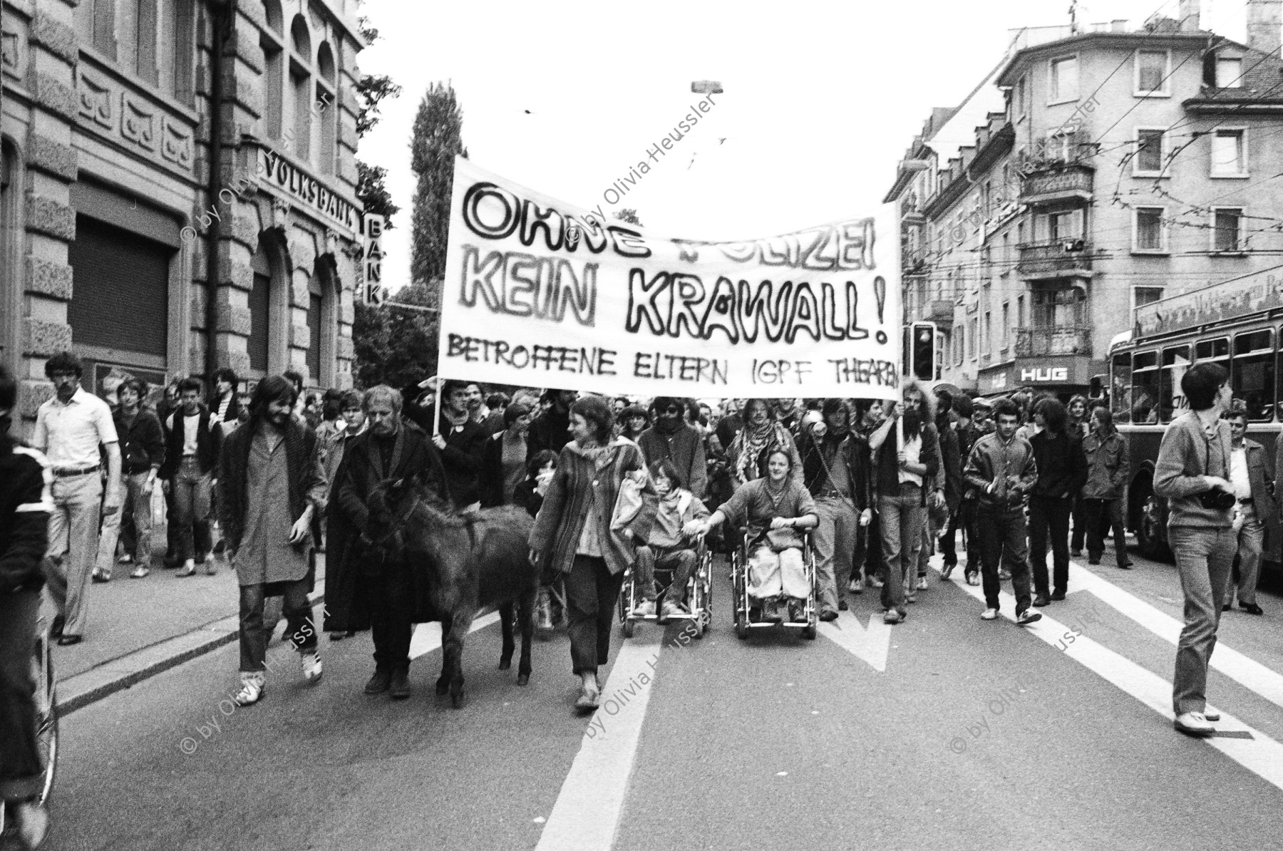 Image of sheet 19800192 photo 30: frtsg. 800190 Unzufriedenen Demonstration mit ca. 7000 Personen führt am geschlossenen und verriegelten AJZ vorbei. Pfarrer Ernst Sieber mit Esel. Transparent Spruchband ' Ohne Polizei kein Krawall . Betroffene Eltern IGF. Frau im Rollstuhl.
Stacheldraht. Langstrassen Brücke Photographen. Mann mit weisser Fahne immitiert und kopiert den Friedensapostel Max Daetwyler
Zürich 1980 youth movement protest
√
Jugendbewegung Bewegig AJZ Zürcher Jugendunruhen Demonstrationen

© 1980, by OLIVIA HEUSSLER / www.clic.li