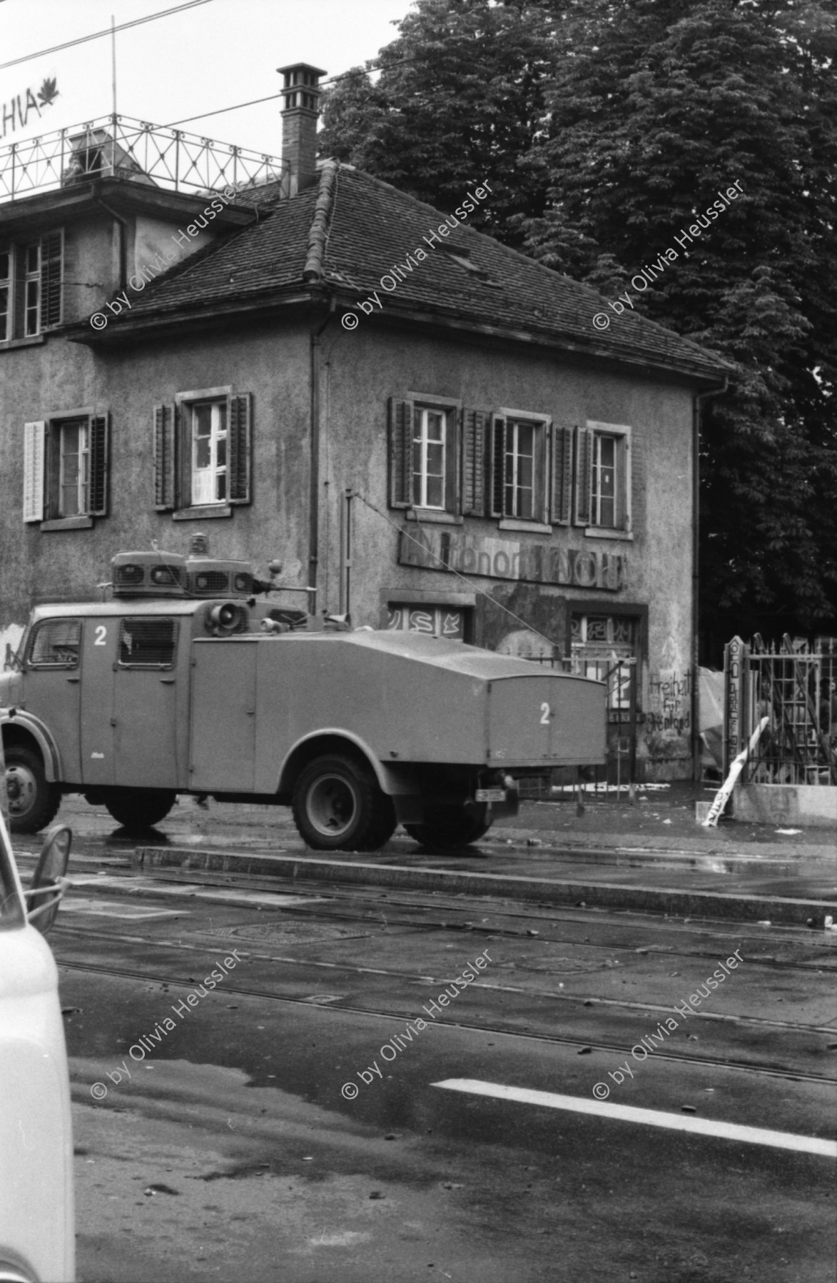 Image of sheet 19800302 photo 29: Vor dem AJZ versammeln sich rund 200 Personen, um für die Einstellung der Strafverfahren zu demonstrieren. Der unbewilligte Demonstrationszug wird von der Polizei aufgelöst: Massive Auseinandersetzungen zwischen den Bewegten und der Polizei, die bis am Sonntagmorgen andauern. Mehr als hundert Personen werden verhaftet. In der folgenden Woche wird in den Medien über das polizeiliche Vorgehen heftig diskutiert.
Massiver Auftritt der Polizei mit ihren Fahrzeugen auf der Langstrasse und Limmatstrasse von einem Balkon aufgenommen. Weit und breit keine Demonstration aber Polizei. in Zweier-Reihe mit Korb Schilder und Helmen. Wasserwerfer im Einsatz am Limmatplatz Barrikade unter Eisenbahnbrücke des Viadukt Bus VBZ steht. Tränengas Patrone.

Jugendbewegung Bewegig AJZ Zürcher Jugendunruhen Demonstrationen
Zürich youth movement protest 1980