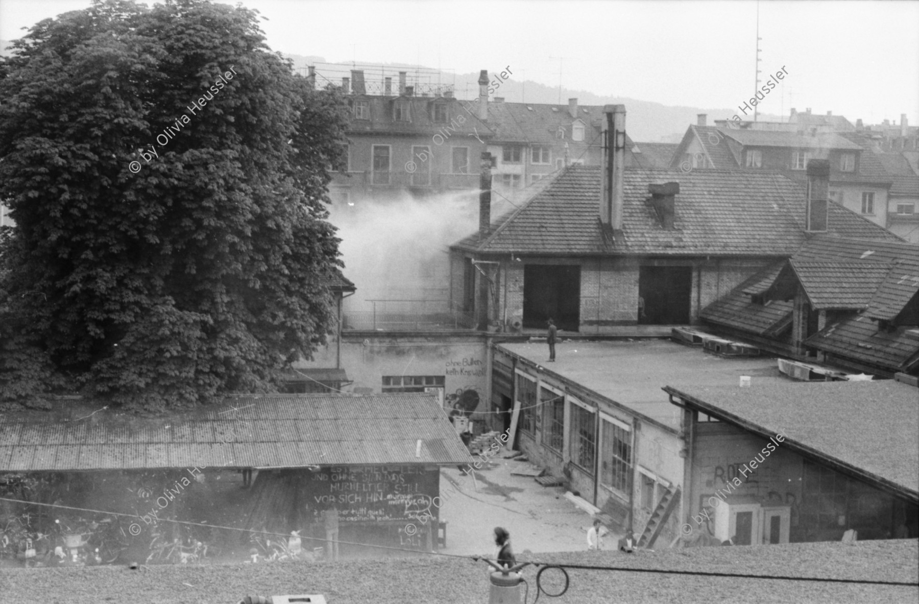 Image of sheet 19800305 photo 20: Vor dem AJZ versammeln sich rund 200 Personen, um für die Einstellung der Strafverfahren zu demonstrieren. Der unbewilligte Demonstrationszug wird von der Polizei aufgelöst: Massive Auseinandersetzungen zwischen den Bewegten und der Polizei, die bis am Sonntagmorgen andauern. 124 Personen werden verhaftet. In der folgenden Woche wird in den Medien über das polizeiliche Vorgehen heftig diskutiert. 
12 Stunden Demonstration. Das AJZ ist vollständig mit Tränengas und Rauch eingehüllt. Auf dem Dach flüchten Leute, die direkt angespritzt werden aus dem Wasserwerfer mit Tränengas Gemisch. Verletzter wird weggetragen. Leute wollen vom Dach springen.
Jugendbewegung Bewegig Zürcher Jugendunruhen Demonstrationen
Zürich youth movement protest 1980 teargas police panic Limmatstrasse Kreis fünf Schweiz Switzerland Europe