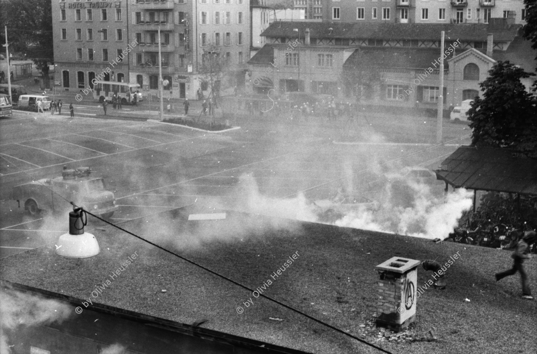 Image of sheet 19800305 photo 31: Vor dem AJZ versammeln sich rund 200 Personen, um für die Einstellung der Strafverfahren zu demonstrieren. Der unbewilligte Demonstrationszug wird von der Polizei aufgelöst: Massive Auseinandersetzungen zwischen den Bewegten und der Polizei, die bis am Sonntagmorgen andauern. 124 Personen werden verhaftet. In der folgenden Woche wird in den Medien über das polizeiliche Vorgehen heftig diskutiert. 
12 Stunden Demonstration. Das AJZ ist vollständig mit Tränengas und Rauch eingehüllt. Auf dem Dach flüchten Leute, die direkt angespritzt werden aus dem Wasserwerfer mit Tränengas Gemisch. Verletzter wird weggetragen. Leute wollen vom Dach springen.
Jugendbewegung Bewegig Zürcher Jugendunruhen Demonstrationen
Zürich youth movement protest 1980 teargas police panic Limmatstrasse Kreis fünf Schweiz Switzerland Europe