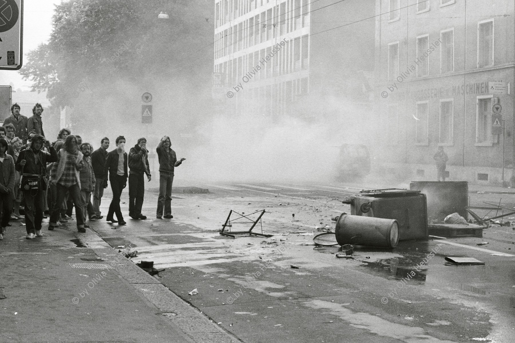 Image of sheet 19800306 photo 7: Vor dem AJZ versammeln sich rund 200 Personen, um für die Einstellung der Strafverfahren zu demonstrieren. Der unbewilligte Demonstrationszug wird von der Polizei aufgelöst: Massive Auseinandersetzungen zwischen den Bewegten und der Polizei, die bis am Sonntagmorgen andauern. 124 Personen werden verhaftet. In der folgenden Woche wird in den Medien über das polizeiliche Vorgehen heftig diskutiert.

Die Limmatstrasse vor dem AJZ gleicht einem Schlachtfeld. Barrikaden. Rauch. Container liegen am Boden. 12. Juli 1980
Zürich youth movement protest 1980 √ Kreis 5 fünf Schweiz Switzerland Europe