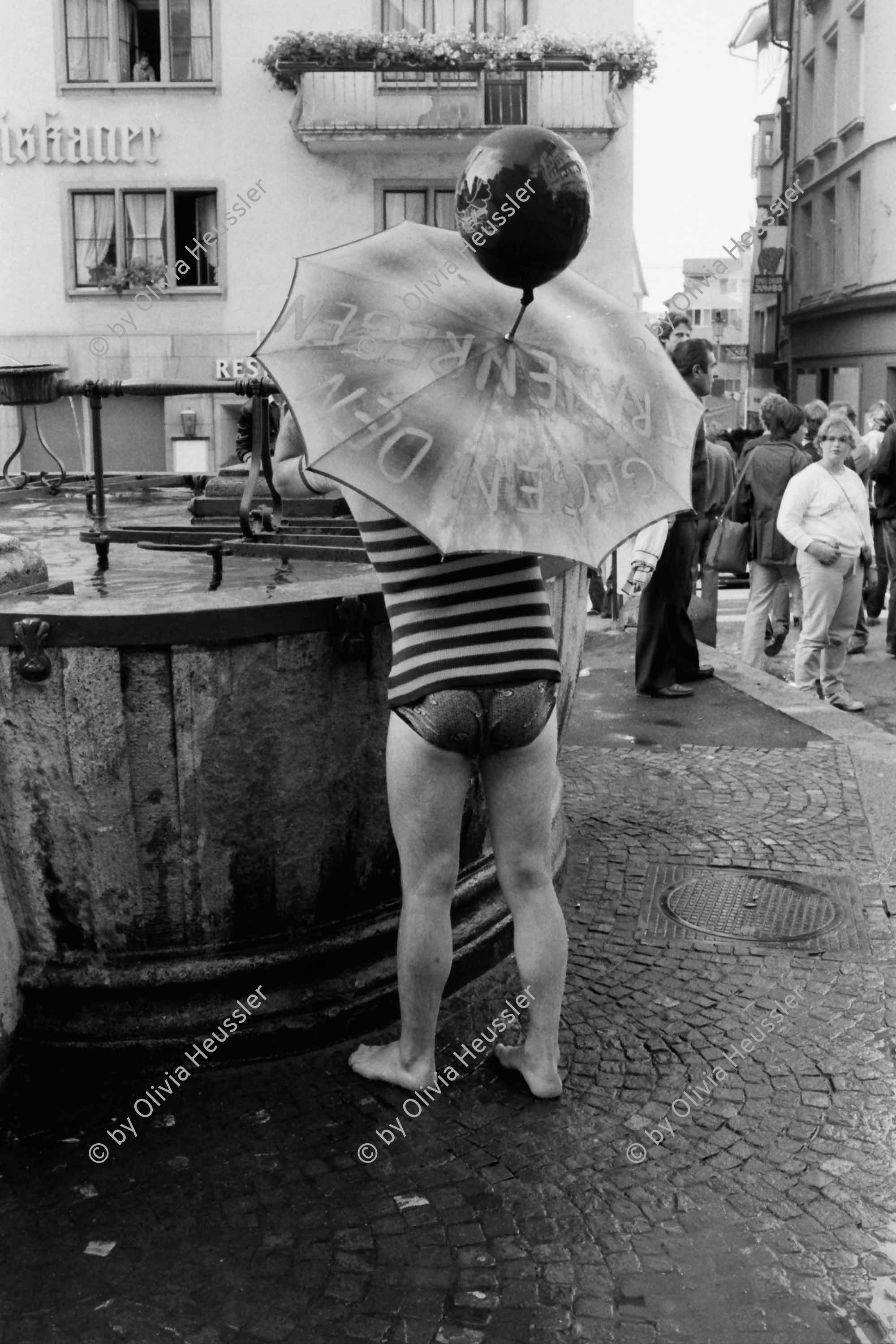 Image of sheet 19800361 photo 31: Demo zur Schliessung des AJZ. Mann spielt mit Wasserzuber und Schirm am Brunnen vor dem Franziskaner Hotel im Niederdorf.

Jugendbewegung Bewegig AJZ Zürcher Jugendunruhen Demonstrationen
Zürich Youth movement 1980 √