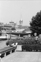 Image of sheet 19800371 photo 9: Mann liest am Zürich-Seeufer neben Dampfschiff in der Sonne vor Quaibrücke mit Mirage Tram 1980 in Zürich.