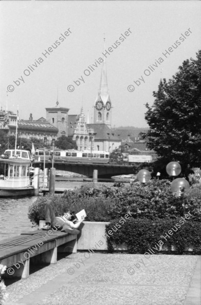 Image of sheet 19800371 photo 9: Mann liest am Zürich-Seeufer neben Dampfschiff in der Sonne vor Quaibrücke mit Mirage Tram 1980 in Zürich.