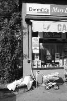 Image of sheet 19800400 photo 0: Kinderwagen  und Spielsachen vor einem Kiosk. Güterwagen überqueren die Strasse.