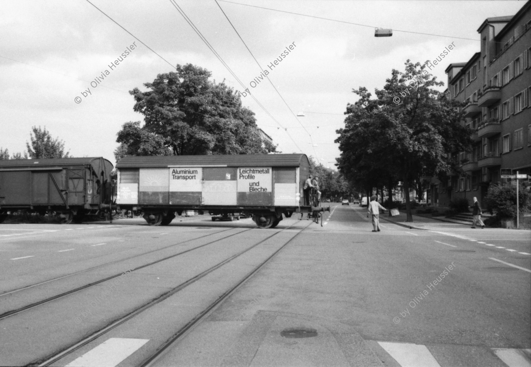 Image of sheet 19800400 photo 10: Kinderwagen  und Spielsachen vor einem Kiosk. Güterwagen überqueren die Strasse.