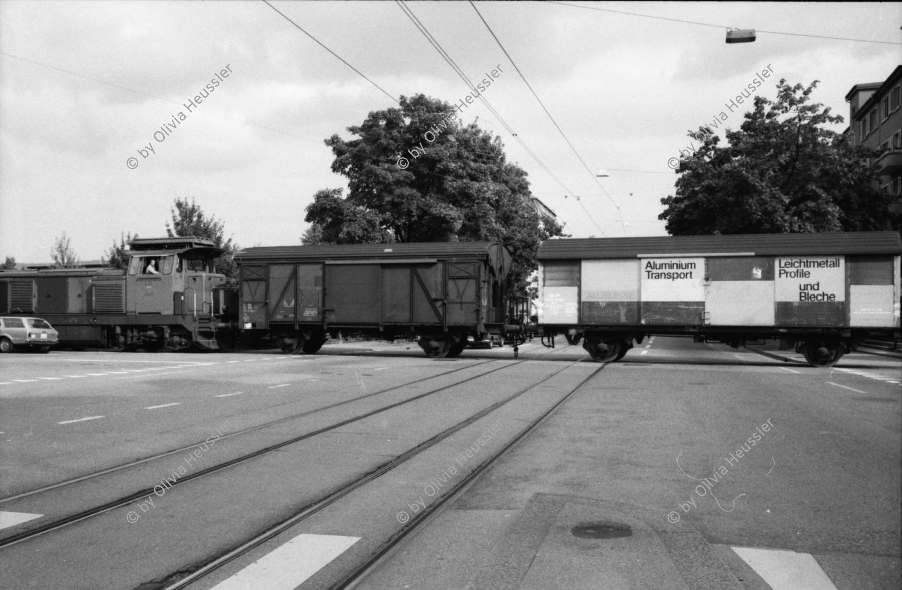 Image of sheet 19800400 photo 11: Kinderwagen  und Spielsachen vor einem Kiosk. Güterwagen überqueren die Strasse.