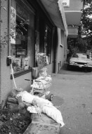 Image of sheet 19800400 photo 5: Kinderwagen  und Spielsachen vor einem Kiosk. Güterwagen überqueren die Strasse.