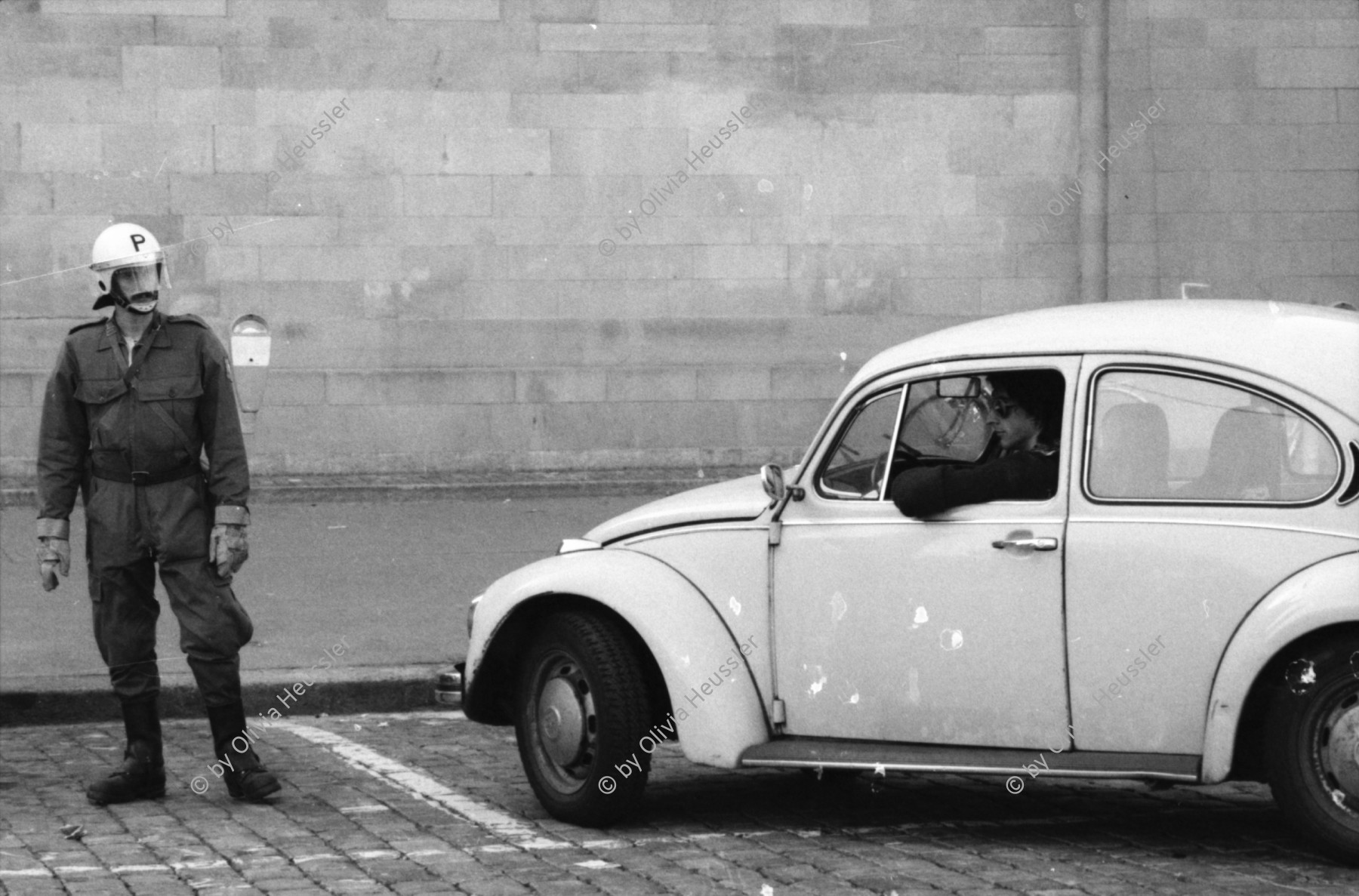 Image of sheet 19800483 photo 1: Ein Fahrer in einem VW Kaefer vor einem Polizeibeamten, Zuerich 1980.