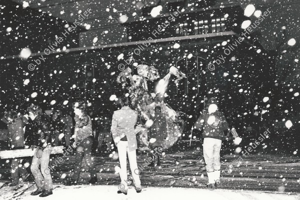 Image of sheet 19800621 photo 1: im Kreis 4 an der Stauffacherstrasse in der Nacht mit Schnee und Feuer. Schneeflocken fliegen auf die den Boden. Schwarze Fahnen im Wind.