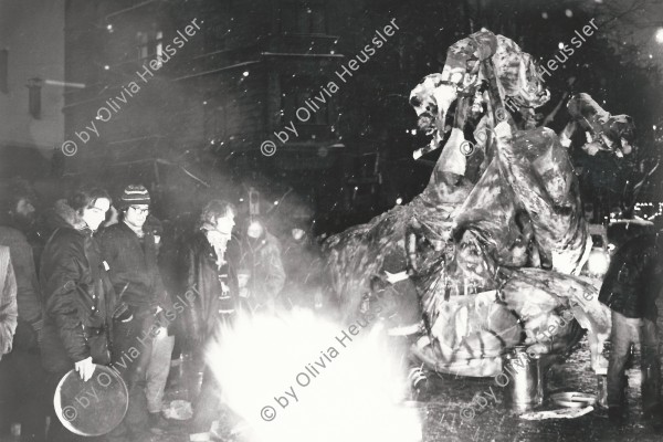 Image of sheet 19800621 photo 27: Luft und Lärm an der Stauffacherstrasse Nacht und Schnee Feuer Aktion auf. Grosse Schneeflocken fliegen auf die den Boden. Schwarze Fahnen im Wind. Ein Autofressendes Monster steht da. Die Polizei steht schon bereit. CV
Jugendbewegung Bewegig AJZ Zürcher Jugendunruhen Demonstrationen
Youth movement Zürich 1980 √