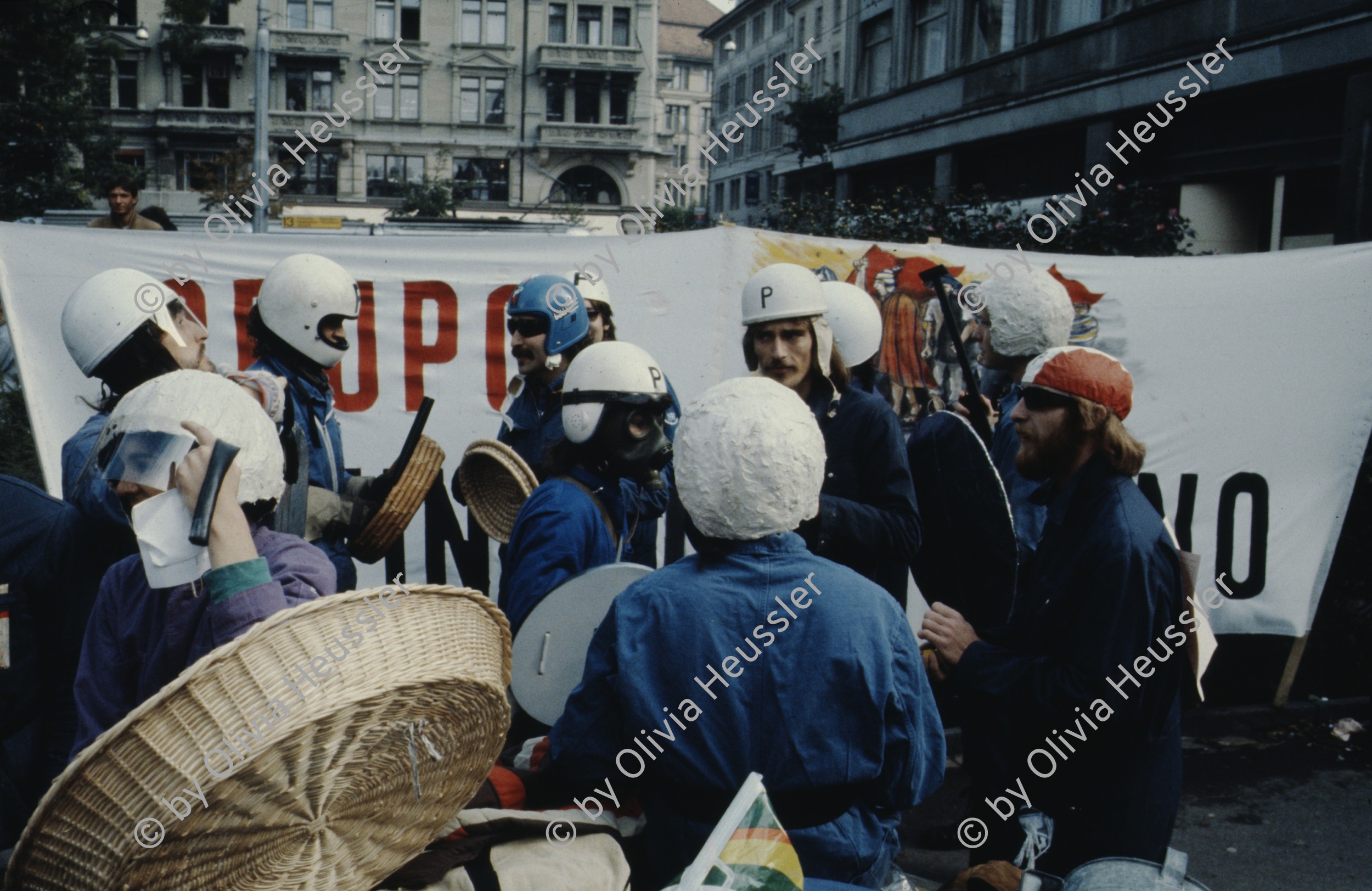 Image of sheet 19803000 photo 34: Jugendliche protestieren in einer Polit Performance, mit Korb-Schilder und Helm als Polizei Grenadiere verkleidet an der Bahnhofstrasse 1980 in Zuerich.
Kreativ Action