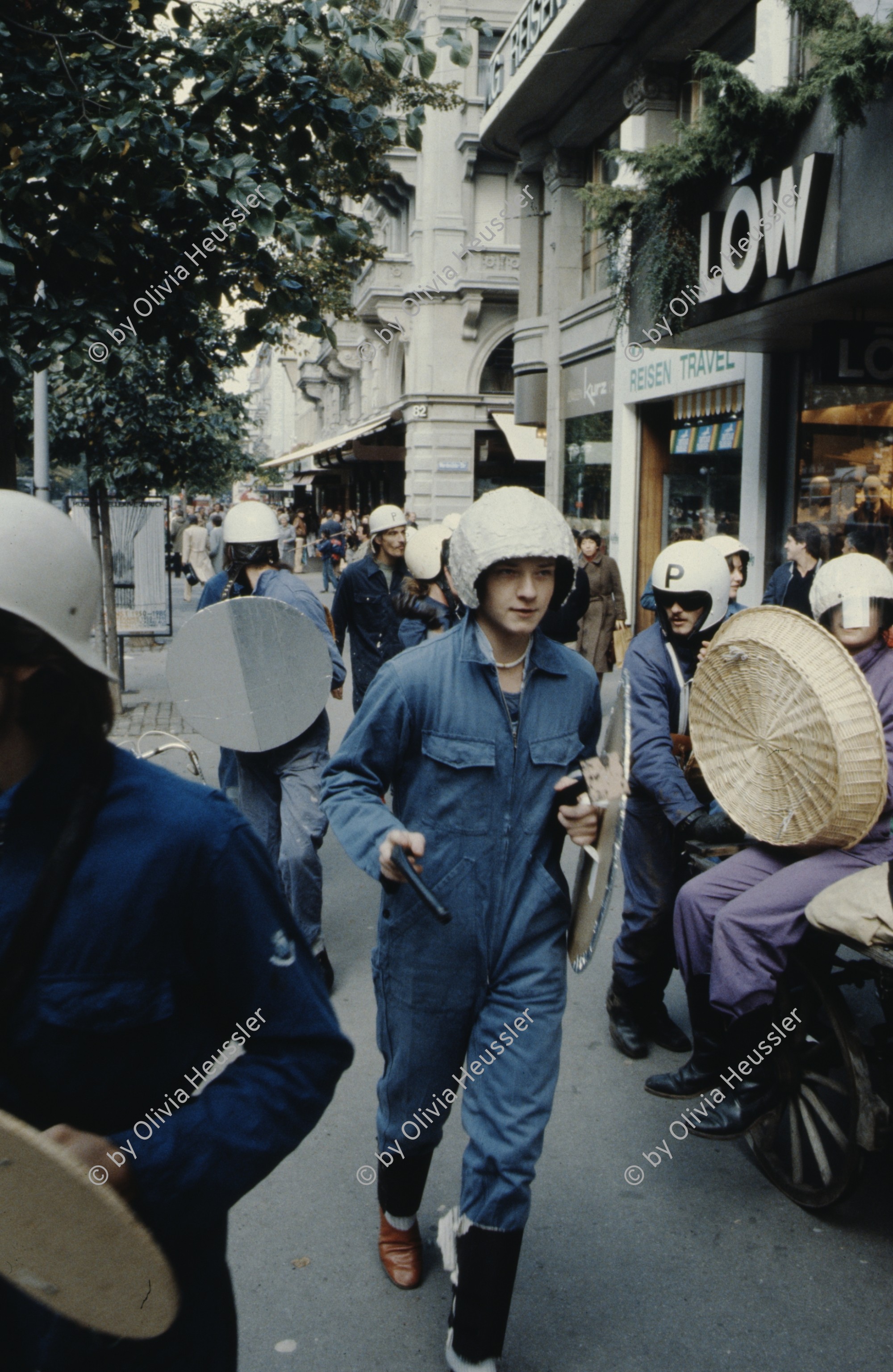 Image of sheet 19803000 photo 36: Jugendliche protestieren in einer Polit Performance, mit Korb-Schilder und Helm als Polizei Grenadiere verkleidet an der Bahnhofstrasse 1980 in Zuerich.
Kreativ Action
creative Action Jugendbewegung Youth Movement Protest Art Polit Performance Achmed von Warthburg