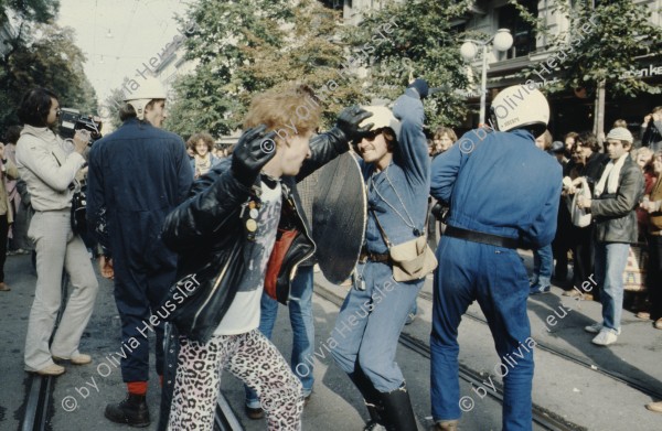 Image of sheet 19803000 photo 40: Jugendliche protestieren in einer Polit Performance, mit Korb-Schilder und Helm als Polizei Grenadiere verkleidet an der Bahnhofstrasse 1980 in Zuerich.
Kreativ Action creative Action Jugendbewegung Youth 
Juerg Hasler filmt 
Movement Protest Art Polit Performance