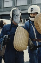 Image of sheet 19803000 photo 46: Jugendlicher maskiert als Stadtrat Sigi Widmer und mit Korb-Schild und Helm als Polizei Grenadiere verkleidet an der Bahnhofstrasse 1980 in Zuerich.
creative Action Jugendbewegung Youth Movement Protest Art Polit Performance
-----
Auf der Pestalozziwiese findet eine Informationsaktion statt. Die Stadtpolizei lässt die dialogbereiten AJZ-AnhängerInnen, die mit fingierten Auseinandersetzungen ein spontanes Strassentheater mit gemimten PolizistInnen inszenieren, nicht gewähren und verhaftet 144 Personen.
Nachdem diese Aktion durch die neue Einkreistaktik der Polizei verhindert worden ist, machen sich in den gemässigten Kreisen der Bewegung Resignation, Enttäuschung und Verzweiflung breit.
Heinz Ning.