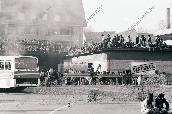 Image of sheet 19810162 photo 6: frtsg.810161 21.März 1981
An der bewilligten «Frühlingsdemonstration» nehmen rund 8000 Personen teil. Als der Zug das AJZ erreicht, dringen Tausende in das Areal des AJZ ein, und besetzen es. Während ein Teil des Zuges seinen Weg Richtung Helvetiaplatz fortsetzt. Am Abend räumt die Polizei das Gelände des AJZ: Gewalttätige Auseinandersetzungen und Sachbeschädigungen in der Gegend des Hauptbahnhofs. Limmatstrasse AJZ Stürmung und Besetzung Stacheldraht. Wir temporären und du? Plakat. 
 
Jugendbewegung Zürcher Bewegung Autonomes Jugendhaus
Youth movement Zürich 1981 √ Switzerland Schweiz Europe Kreis fünf