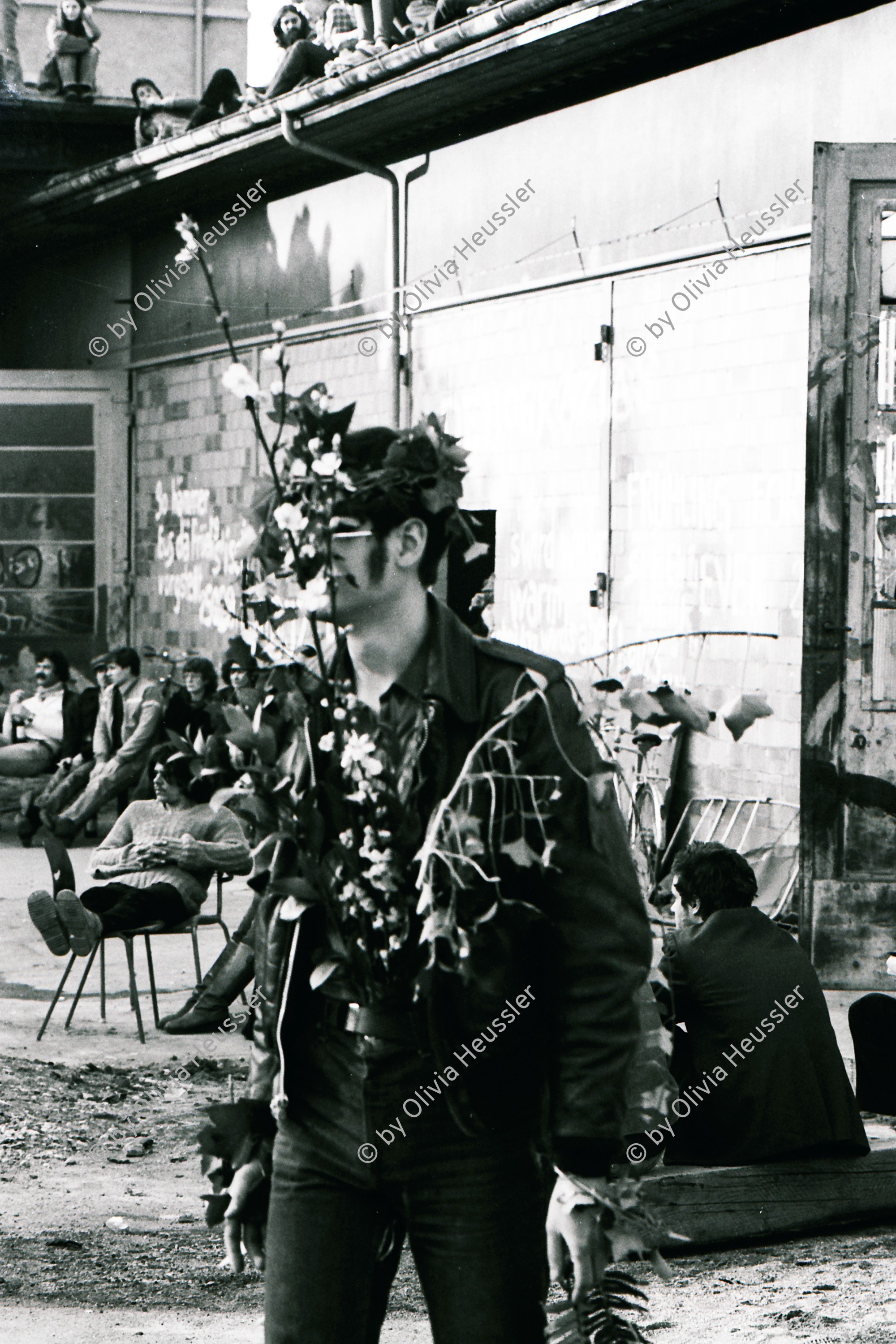 Image of sheet 19810170 photo 5: frtsg 810163 
AJZ Wiederbelebt Mann hat sich dekoriert Dekoration.
An der bewilligten «Frühlingsdemonstration» nehmen rund 8000 Personen teil. Als der Zug das AJZ erreicht, dringen Tausende in das Areal des AJZ ein, während ein Teil des Zuges seinen Weg Richtung Helvetiaplatz fortsetzt. Am Abend räumt die Polizei das Gelände des AJZ: Gewalttätige Auseinandersetzungen und Sachbeschädigungen in der Gegend des Hauptbahnhofs.
Frühlingsdemonstration und Besetzung AJZ an der Limmatstrasse 18-20 Auf Dach Terasse mit Transparent Autonomes Jugendzentrum Jugendunruhen Bewegung Jugendbewegung 
Youth movement Zürich 1981 √