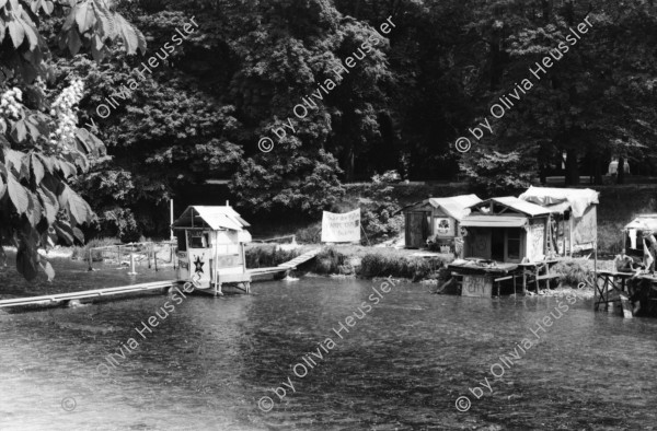 Image of sheet 19810191 photo 11: Aufbau AJZ Küche und Dach Junge bauen. Chaotikon in der Sihl Fluss Wasser Protest gegen Wohnungsnot Wohn Installation Zürich Feuer 

Baraken siedlung auf Pfosten, Küche  Christoph Müller Urs Morf Züri Leu housing 1981 Switzerland swiss Schweiz Europe youth movement Wohnen Kochen