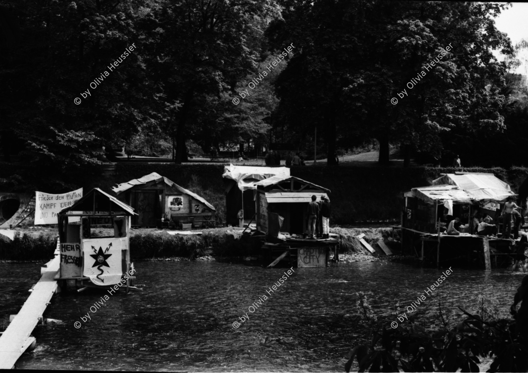 Image of sheet 19810191 photo 12: Junge bauen Chaotikon in der Sihl Fluss Wasser Protest gegen Wohnungsnot Wohn Installation Zürich Feuer 

Baraken siedlung auf Pfosten,housing 1981 Switzerland swiss Schweiz Europe youth movement Wohnen Zürich Kreis 5