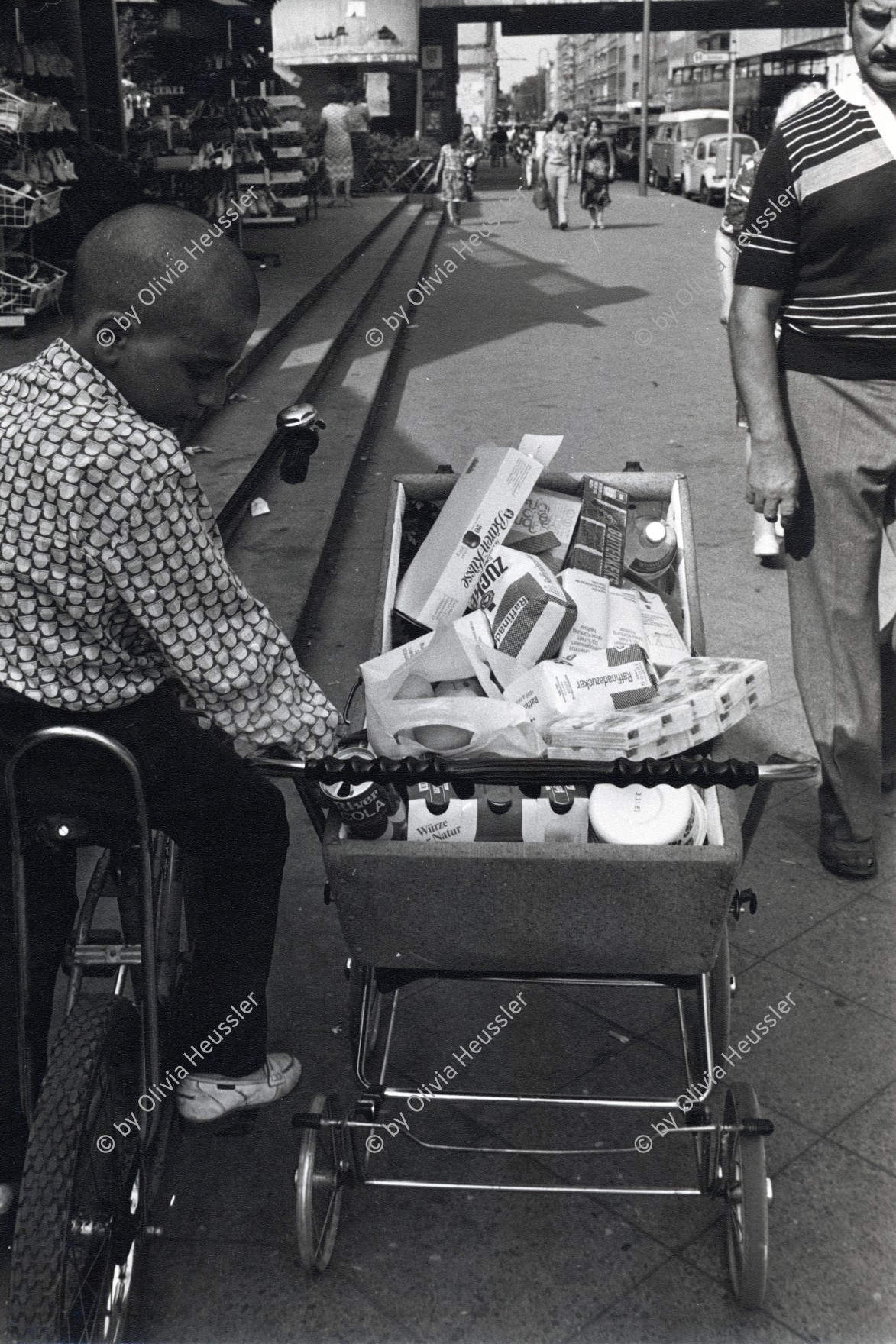 Image of sheet 19810380 photo 21: Junge auf Fahrrad Velo mit gefüllten Kinderwagen voller Nahrungsmittel.  Deutschland. Berlin Westdeutschland 1981 √ Einkauf Shoping 
west germany young man adult baby wagon trolley

© 1981, by OLIVIA HEUSSLER / www.clic.li