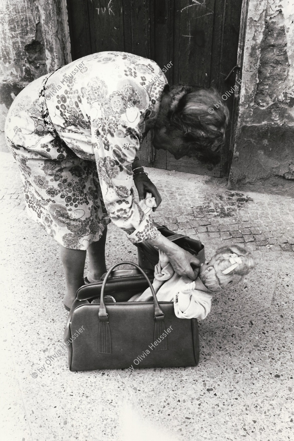 Image of sheet 19810380 photo 25: Alte Frau füttert ihre Puppe in der Einkaufstasche mit Banane. 
Berlin West Westberlin
retired old woman baby doll feeding in shopper
Deutschland 1981 √
© 1981, by OLIVIA HEUSSLER / www.clic.li