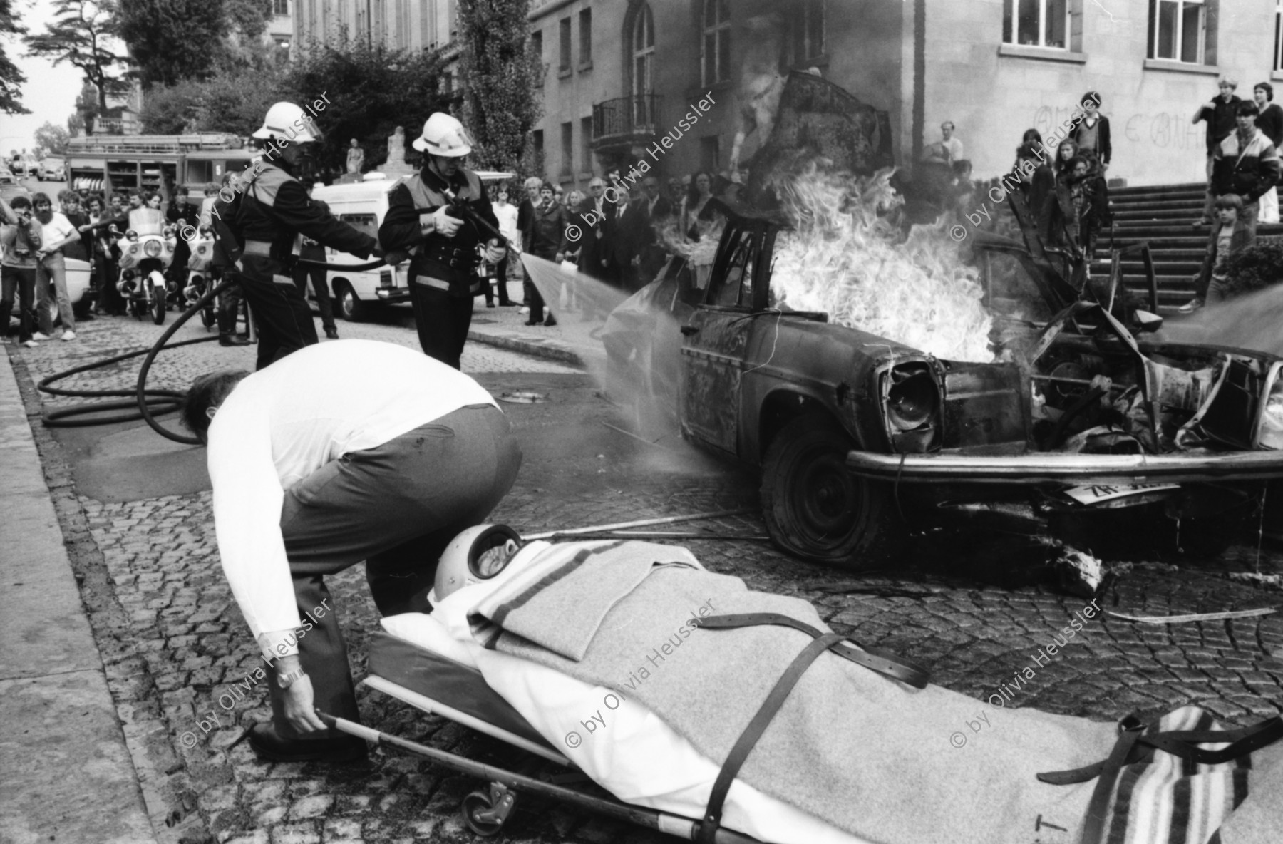 Image of sheet 19810460 photo 32: Feuerwehr löscht Brand auf Filmset mit Yves Poisset Espion l'ève toi. Motorrad fahrer wird von Sanität mit Helm abgeführt. Zürich 1981