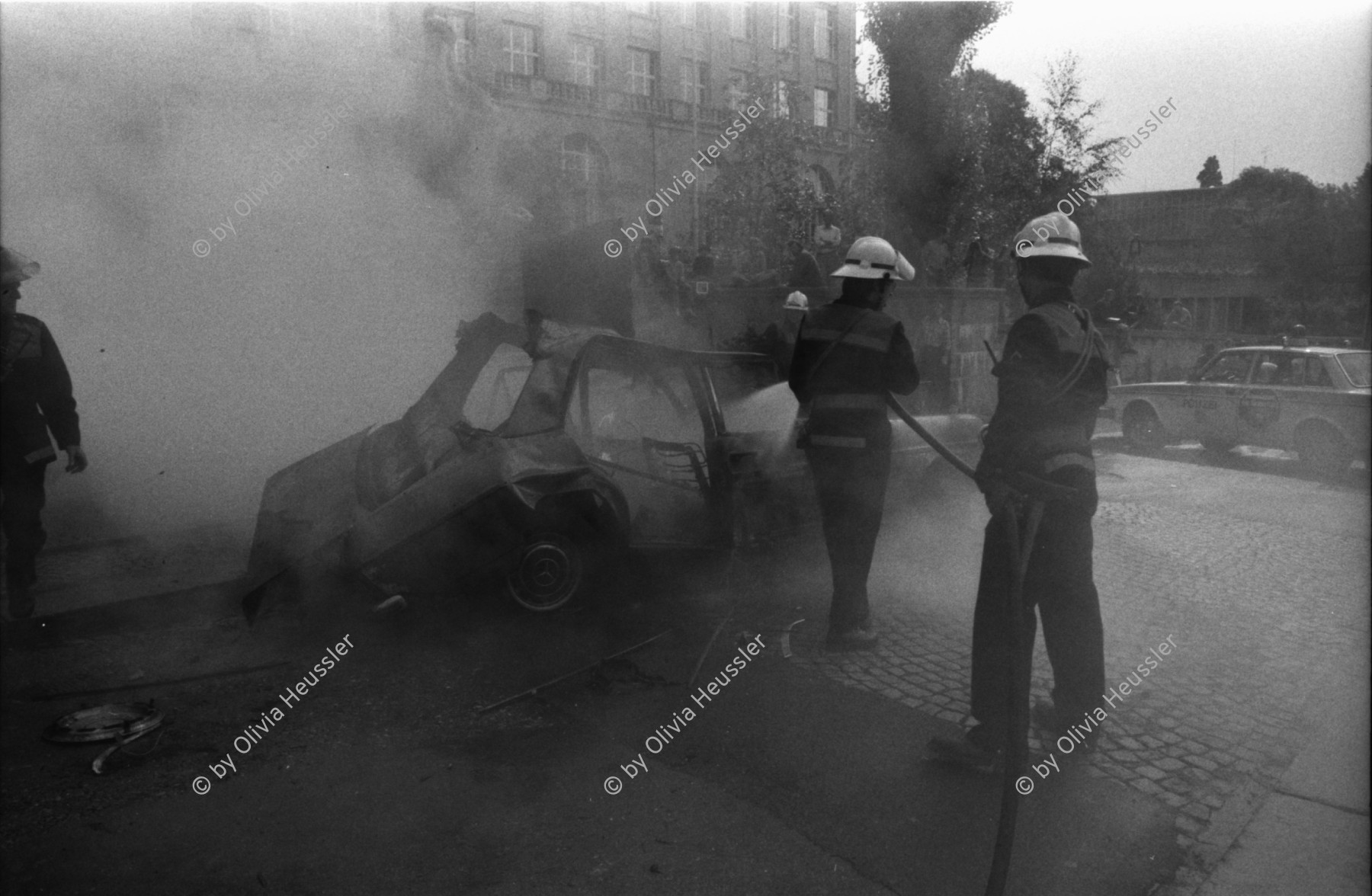 Image of sheet 19810470 photo 2: Feuerwehr löscht brennender Mercedes Benz auf Filmset Yves Poisset. Zürich 1981