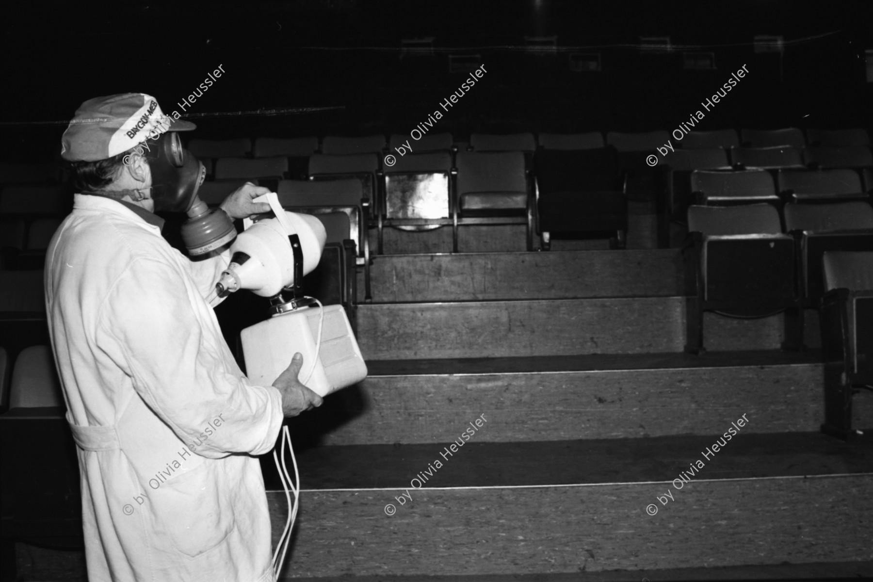 Image of sheet 19810572 photo 19: Während einer grossangelegten Reinigung im Kino Xenix im Zürcher Autonomen Jugendhaus (AJZ) in Zürich.1981
Das AJZ wird von einem Mann der Stadt mit Chemie besprayt und gesäubert. Er trägt Gasmaske und Gerät im Kinosaal.