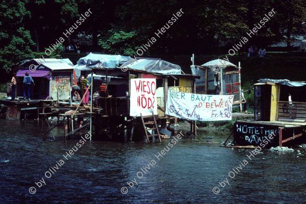 Image of sheet 19813002 photo 1: Chaotikon in der Sihl. Protest gegen Wohnungsnot Wohn Installation Zürich occupied house √
Barraken siedlung auf Pfosten, Küche Kreis fünf 1981 Wohnen housing banner river protest settlement Schweiz Switzerland Europe 
© 1981, OLIVIA HEUSSLER / www.clic.li