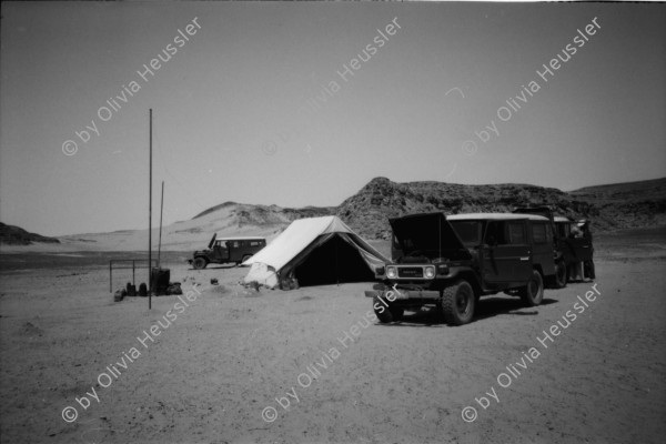 Image of sheet 19820140 photo 9: Drei Toyota Landcruiser Offroader stehen vor einem Kamel Skelett. Ein Wüstenbefpflanzungsprojekt. Ein Kanal ist in Bau um Süsswasser aus dem Nil zu führen. Junge und Mädchen bringen uns Tee. Vor dem Haus. 2 Lastwagen Motoren dienen als Elektrizitätswerk für die ganze Stadt. Kinder Gruppe. Kapitän auf dem Nil. Ein Jeep ist im Sand steckengeblieben. Till Lincke trocknet im Wind ab. Ein Pumpwerk für Oel. Sonnenuntergang. Mobil Oel Station Tankstelle.
Mit Bahnwagen. Mann reitet auf Esel neben einem Lastwagen. Wir fahren an Militärposten vorbei dem Nil entgegen. zwei Männer schauen einem Schiff nach.