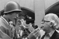 Image of sheet 19830140 photo 6: Junge Neofaschisten Neonazis am Rande einer Demonstration diskutieren mit einem Rentner und wollen nicht fotografiert werden. 
Einer trägt ein Militärhelm auf dem Kopf.
Bern 1983 √