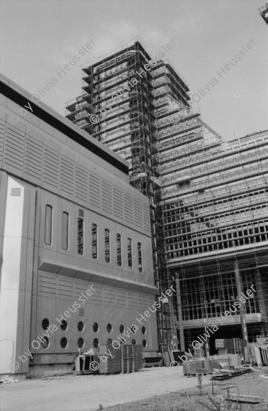 Image of sheet 19830150 photo 2: WOZ Schlieren und Kantonsschule Urdorf. Postgebäude Mülligen. Wagi Schlieren. Dorfplatz. Riegelhaus in Schlieren. Auto und Verkehr Strasse. Mann mit Gewehr und Hund vom Schweizer Künstler und Bildhauer Kurt Lorenz Metzler wirbt für die Waffenfabrik Fortschritt Zürich 1983  Autobahn in Bau an  Schulhaus vorbei. Lastkran Kran Kranen und Siedlungen.