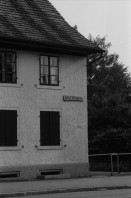 Image of sheet 19830150 photo 21: WOZ Schlieren und Kantonsschule Urdorf. Postgebäude Mülligen. Wagi Schlieren. Dorfplatz. Riegelhaus in Schlieren. Auto und Verkehr Strasse. Mann mit Gewehr und Hund vom Schweizer Künstler und Bildhauer Kurt Lorenz Metzler wirbt für die Waffenfabrik Fortschritt Zürich 1983  Autobahn in Bau an  Schulhaus vorbei. Lastkran Kran Kranen und Siedlungen.