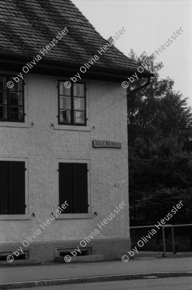 Image of sheet 19830150 photo 21: WOZ Schlieren und Kantonsschule Urdorf. Postgebäude Mülligen. Wagi Schlieren. Dorfplatz. Riegelhaus in Schlieren. Auto und Verkehr Strasse. Mann mit Gewehr und Hund vom Schweizer Künstler und Bildhauer Kurt Lorenz Metzler wirbt für die Waffenfabrik Fortschritt Zürich 1983  Autobahn in Bau an  Schulhaus vorbei. Lastkran Kran Kranen und Siedlungen.