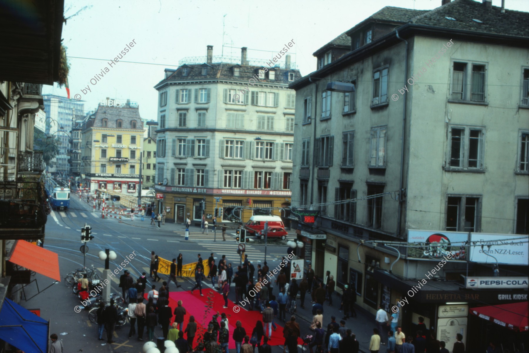 Image of sheet 19833000 photo 1: Am Tor zu Aussersihl
Am Stauffacherplatz Badenerstrasse wird das Eckhaus besetzt. Ein rotes Tuch wird auf den Platz über die Tramschienen der VBZ gelegt. Polizeibeamte nehmen das Tuch auf und die Leute reissen es ihnen aus den Händen. So geht es weiter durch die Stadt. Housing, Besetzung Wohnen, Wohnungsnot, Wohnungsmangel, protest action, art, installation, Stauffacher,  
Zürich Schweiz Switzerland
Exhibition: Zurich, The Eighties Photobastei 2020
»Counter Power« Altkirch 2017 framed pp 40 x 60 cm