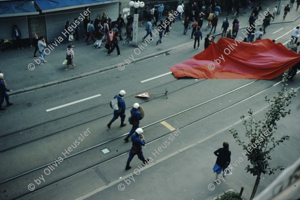 Image of sheet 19833000 photo 10: Am Tor zu Aussersihl
Am Stauffacherplatz Badenerstrasse wird das Eckhaus besetzt. Ein rotes Tuch wird auf den Platz über die Tramschienen der VBZ gelegt. Polizeibeamte nehmen das Tuch auf und die Leute reissen es ihnen aus den Händen. So geht es weiter durch die Stadt. Housing, Besetzung Wohnen, Wohnungsnot, Wohnungsmangel, protest action, art, installation, Stauffacher,  
Zürich Schweiz Switzerland
Exhibition: Zurich, The Eighties Photobastei 2020
»Counter Power« Altkirch 2017 framed pp 40 x 60 cm
co Schmid