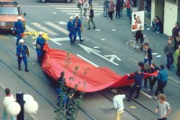 Image of sheet 19833000 photo 6: A la place Stauffacher Badenerstrasse la maison d'angle est occupé. Un tissu rouge est placé sur la place sur les rails de tram. Les agents de police sur le tissu et les gens déchirent hors de leurs mains. Ainsi, il traverse la ville Zürich
© 1983, by OLIVIA HEUSSLER / www.clic.li

Am Tor zu Aussersihl
Am Stauffacherplatz Badenerstrasse wird das Eckhaus besetzt. Ein rotes Tuch wird auf den Platz über die Tramschienen der VBZ gelegt. Polizeibeamte nehmen das Tuch auf und die Leute reissen es ihnen aus den Händen. So geht es weiter durch die Stadt. Housing, Besetzung Wohnen, Wohnungsnot, Wohnungsmangel, protest action, art, installation,
Zürich Schweiz Switzerland
Exhibition: Zurich, The Eighties Photobastei 2020