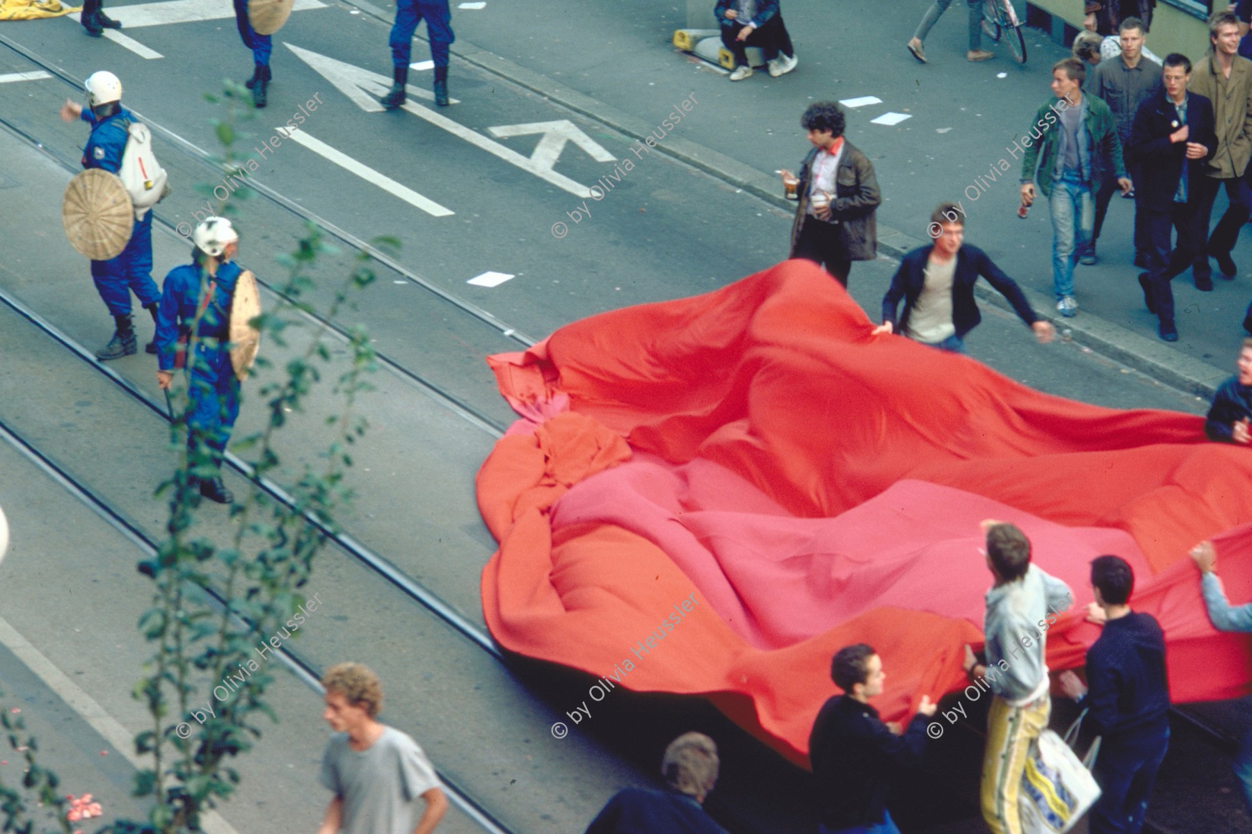 Image of sheet 19833000 photo 7: Am Tor zu Aussersihl
Am Stauffacherplatz Badenerstrasse wird das Eckhaus besetzt. Ein rotes Tuch wird auf den Platz über die Tramschienen der VBZ gelegt. Polizeibeamte nehmen das Tuch auf und die Leute reissen es ihnen aus den Händen. So geht es weiter durch die Stadt. Housing, Besetzung Wohnen, Wohnungsnot, Wohnungsmangel, protest action, art, installation,
Zürich Schweiz Switzerland
Exhibition: Zurich, The Eighties Photobastei 2020