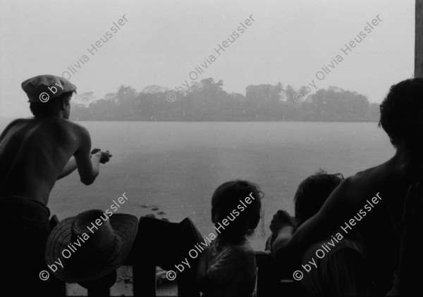 Image of sheet 19840110 photo 10: Schweizer Solidaritäts Brigade in Solentiname. Isla Zapotillo. Boot im See. Wäschebank im See. Vater mit Radio und Knabe. Brigadisten Innen fängt Regen mit Hand auf. Junge besprayt Pferd. Campesino auf Pony mit Rinder. Assentamiento Siedlung. In the house of a settlement for war refugees.
Baseballspieler Baseball Asentamiento Strohhütte Kinder stehen vor Palmwedeln Palmen in Siedlung. Laurel y Galan. (Lorbeer) Machetenschleifen. Adobe haus Hacienda. Einfacher Hausbau in Matagalpa. Nicaragua 1984

Aus: Der Traum von Solentiname/The dream of Solentiname/El sueño de Solentiname