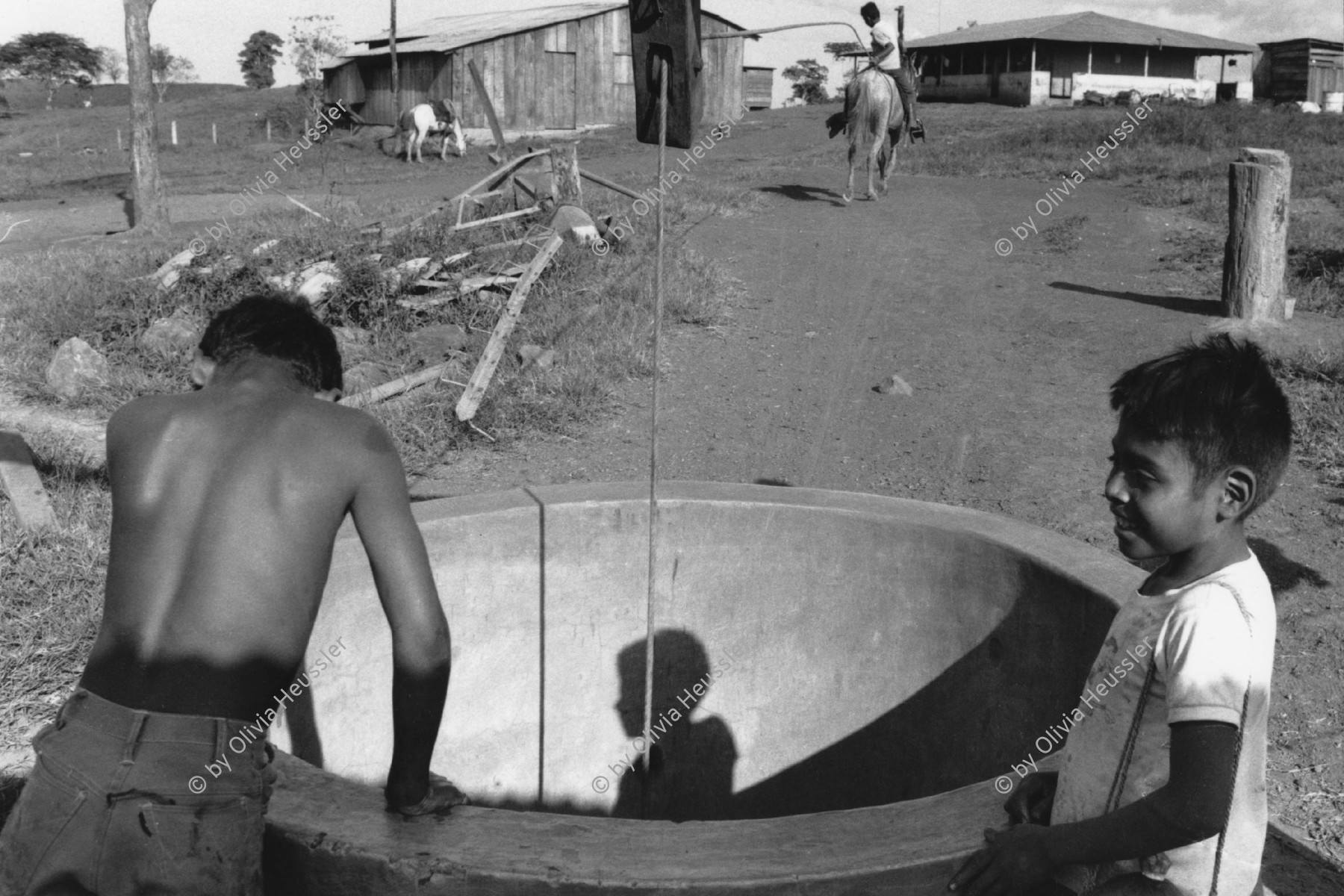 Image of sheet 19840130 photo 19: Zwei Jungen an einem Wasserbrunnen. Der Wassereimer wird mit Hilfe eines Pferdes aus dem Ziehbrunnen gezogen. Rio San Juan Nicaragua 03.84 1984 √