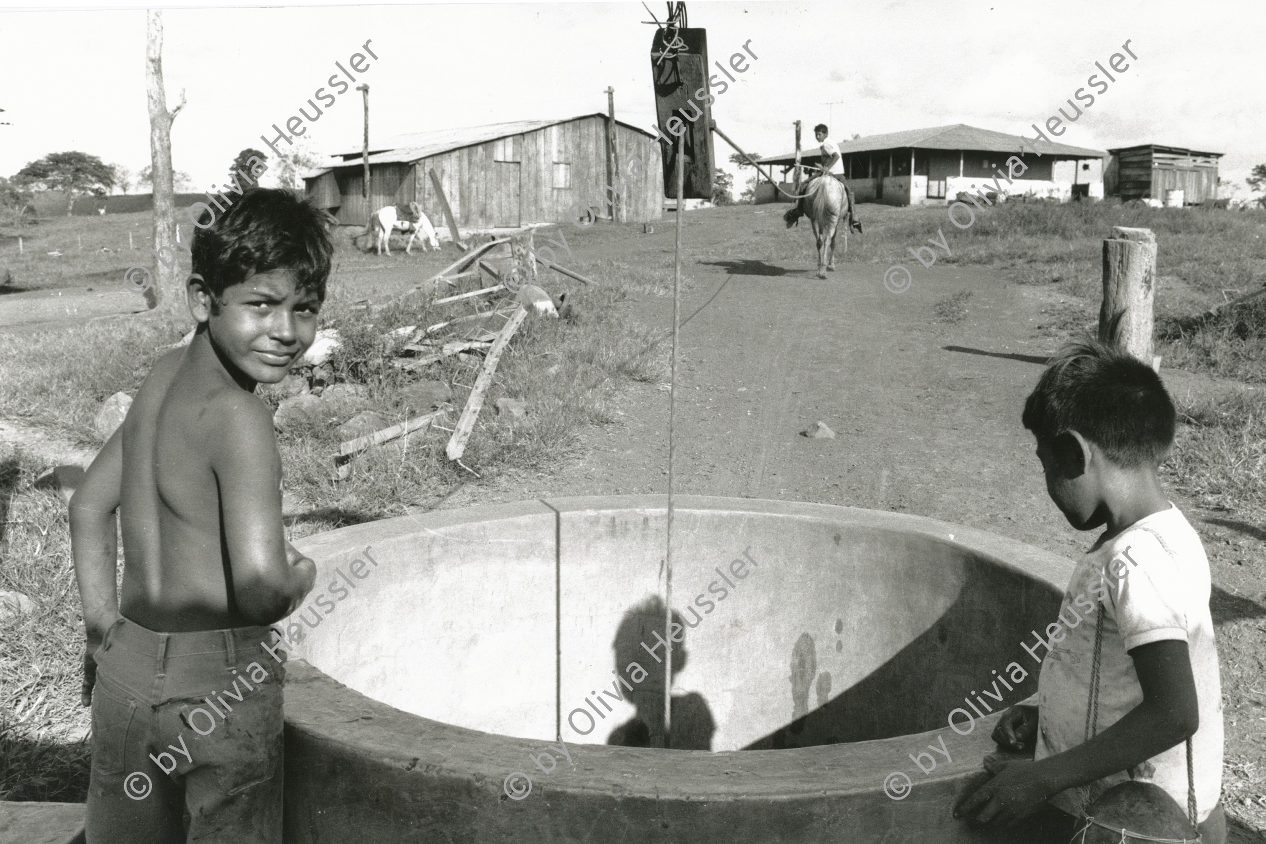 Image of sheet 19840130 photo 20: Zwei Jungen an einem Wasserbrunnen. Der Wassereimer 
Am Brunnen Wasser aus dem Ziehbrunnen holen. Kinder. Nicaragua Rio San Juan 1984 √