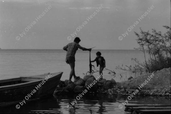 Image of sheet 19840140 photo 34: Sandinist mit unter Leintuch des Ejercito Popular Sandinista. Transparent Schweizer Brigaden. Arbeitsbrigade Brigadisten Brigadistinnen Brigada Suiza. Latrinenbau. Wolfgang Vogel Winterthur Ceibo. Isla de Zapotillo Willy aus Aarau mit Leguane Iguanas. Nicas und Schweizer. Fischerboote. Rudern Insel im Nicaragua see. Solentiname Archipelago de Solentiname. Abendstimmung. Nicaraguaner lernt englisch. Rio San Juan San Carlos Nicaragua 1984